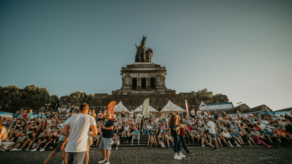 Rhein in Flammen-61-1000x629.jpg © Koblenz-Touristik, Janko. Media
Menschen sitzen am Deutschen Eck © Koblenz-Touristik, Janko. Media